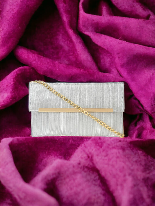 A silver clutch on a pink sheet. 