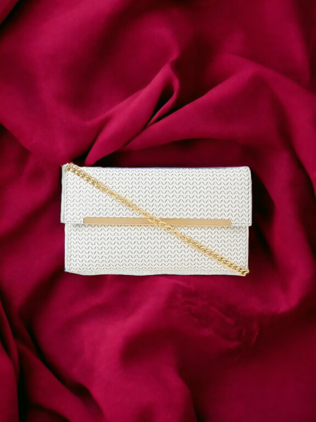 A silver clutch on a red sheet. 