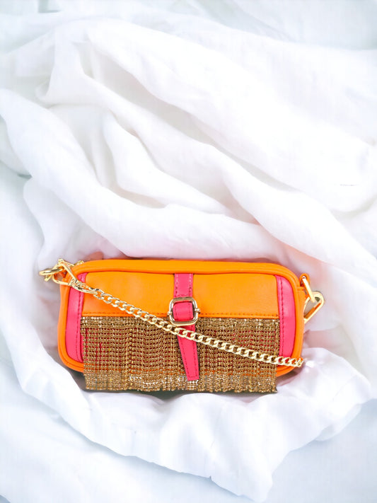 An Orange pink golden fringed fanny pack from Vdesi with a pocket on a white bed.