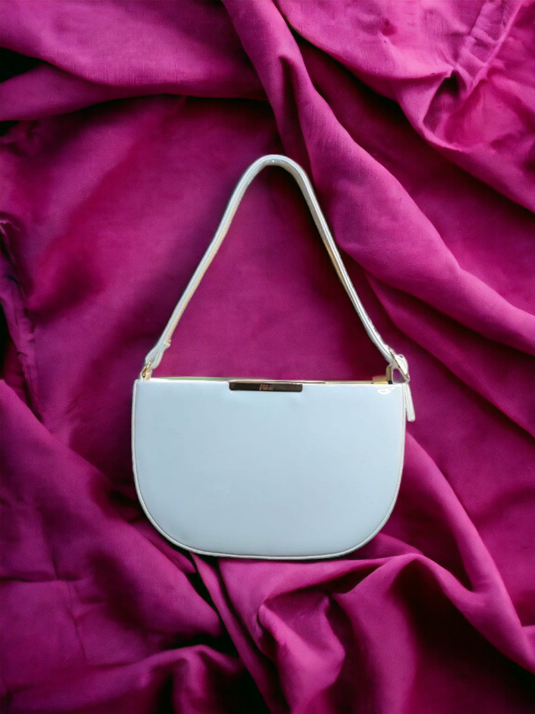 A Vdesi shoulder bag on a plain red sheet. 