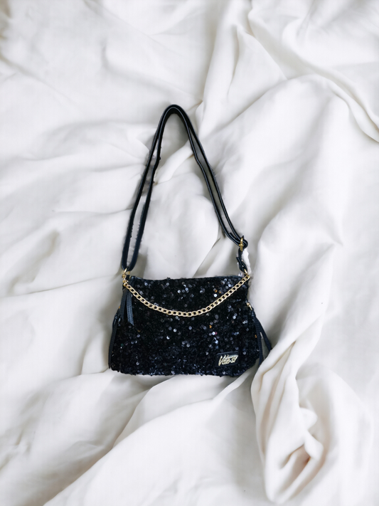 A Vdesi black crossbody bag on a plain white sheet. 